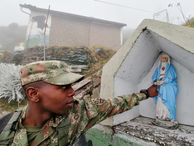 El soldado Kevin Bonilla mientras desafía las condiciones climáticas, a una altura de 4.130 msnm y a una distancia de 6.4 kilómetros de la boca del Nevado del Ruiz, se encomienda a la Virgen.