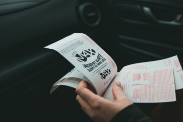 Mujer en un carro con billetes de lotería en la mano.