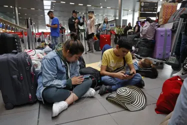 Personas esperan hoy, en el aeropuerto El Dorado de Bogotá (Colombia).   