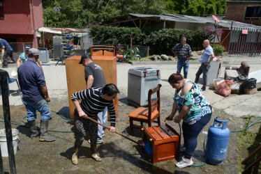 Estela Galvis (izquierda) limpia los muebles de su casa que quedaron repletos de lodo luego de que se desbordara la quebrada Carmelo el lunes festivo en la noche. Los habitantes de la vereda reclaman ayuda del Estado para prevenir una nueva emergencia.