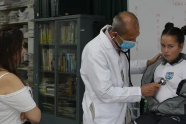 El médico Guillermo González, voluntario en la Fundación Pequeño Corazón, revisó a Valeria Zamora en una brigada efectuada recientemente en Manizales. Ella es alumna de la Institución Educativa Liceo Mixto Sinaí. En la foto aparecen con Diana Carolina Ballesteros, en la biblioteca del sitio.