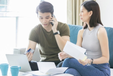 Hombre y mujer revisando deudas en papeles y un computador.