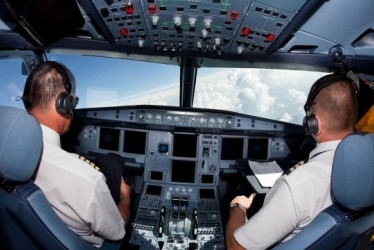 Cabina de un avión en el aire con piloto y copiloto adentro.