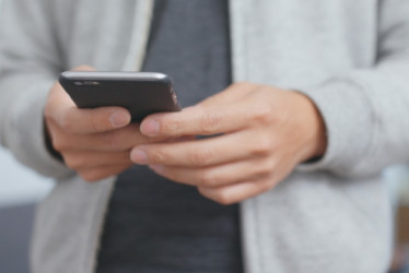 Hombre sosteniendo un celular con ambas manos.