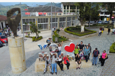 El renovado Parque de Bolívar de Neira muestra escenas como la de estos turistas que llegaron de Cali. Ellos posan al lado del monumento al corcho con la concha acústica como telón de fondo. Esta reúne artistas y público cada ocho días en las retretas y también se ha convertido en la manzana de la discordia de la remodelación: unos dicen que rompe con la arquitectura tradicional, pero otros la defienden.