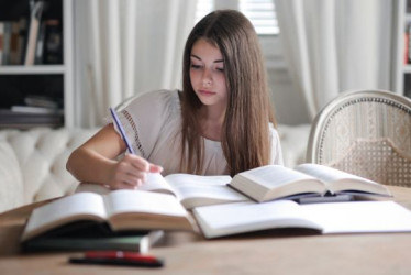 Niña estudiando en un escritorio con libros y cuadernos