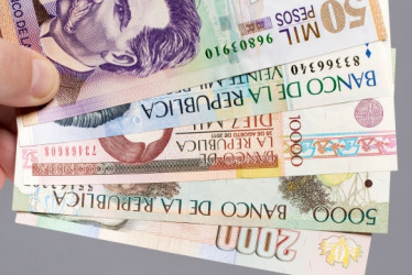 Mano sosteniendo pesos colombianos