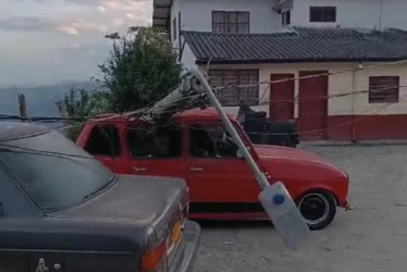 Este carro rojo se vio afectado con la caída de un poste.